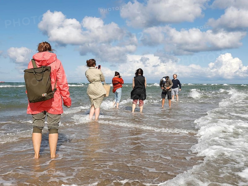 Tourists stand with one foot in the North Sea and one in the Baltic Sea in Grenen or Skagens Gren
