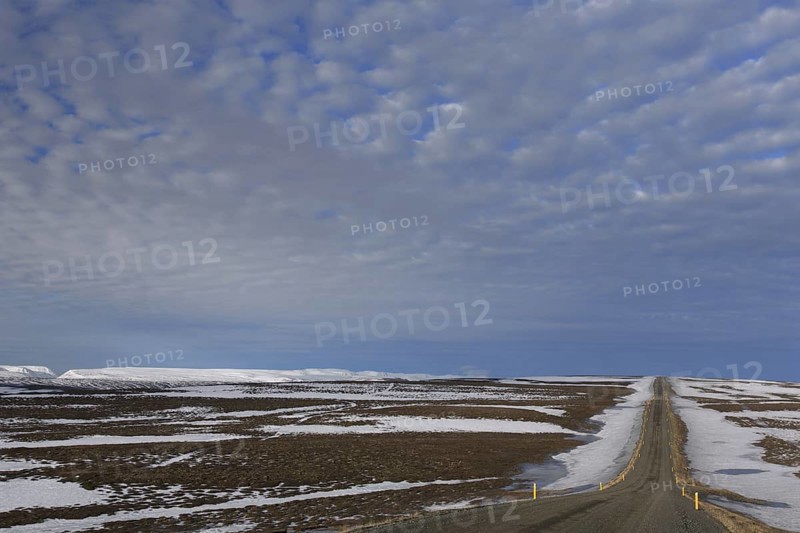 Road leading through the tundra towards the mountain range Lambafjoell