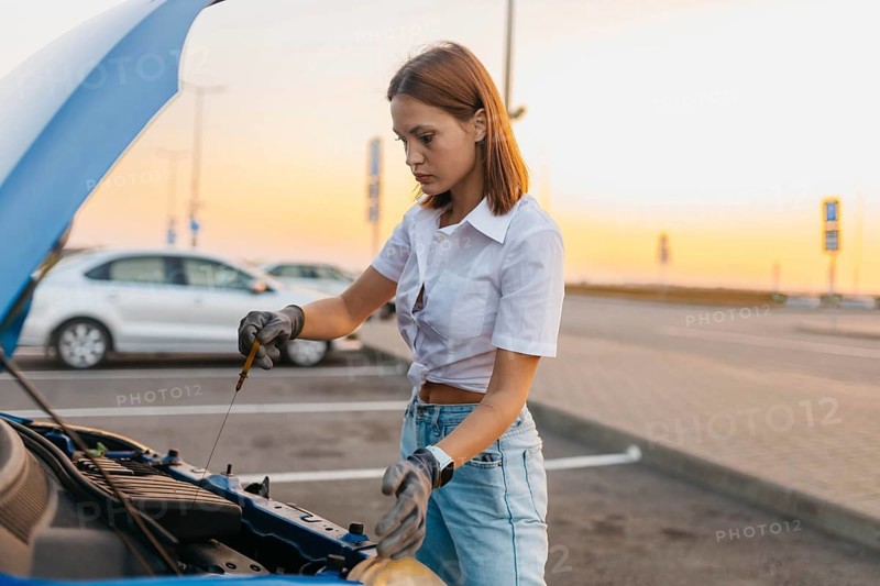 Young beautiful hot girl driver checks oil level