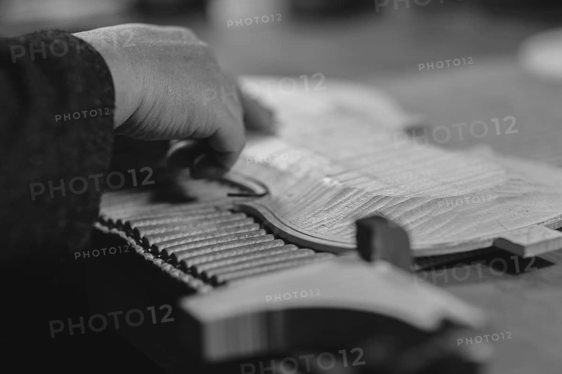 Violinmaker artisan hand in his workshop hold purfling fillet made of evony and ivory or pear wood ready to be inserted in the carved all around the shape for aesthetic touch and prevent cracking