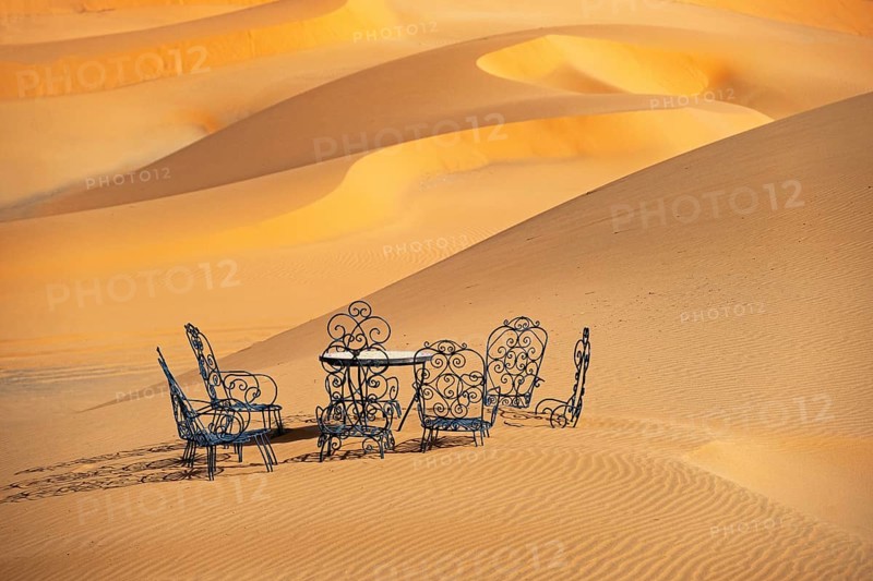Cast iron garden table and lawn chairs in sand dunes of Erg Chebbi in the Sahara Desert near Merzouga
