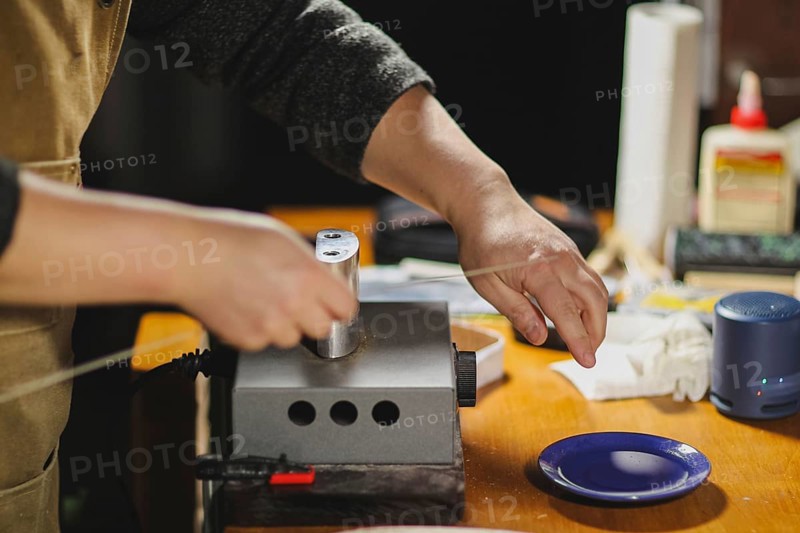 Unrecognizable luthier lute maker artisan both hands performing bend controller purfling strips process in iron tool for a new raw back and front plates of classic handmade violin in his workshop in Cremona