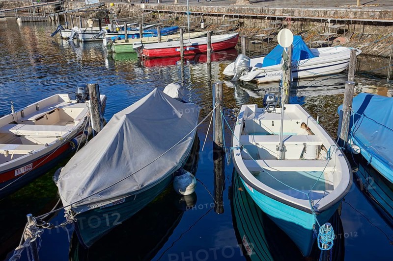 Motorboats moored in the harbour of Ascona and partially protected by a tarpaulin