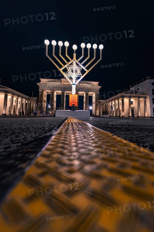 Menorah in front of the Brandenburg Gate at night with festive lighting