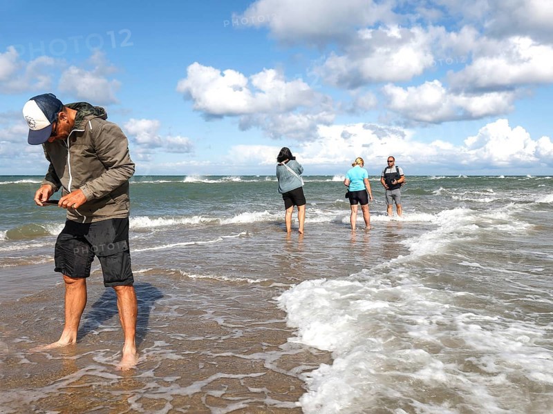Tourists stand with one foot in the North Sea and one in the Baltic Sea in Grenen or Skagens Gren