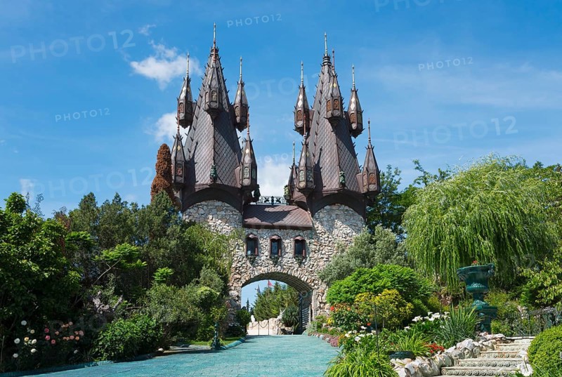 A fairytale castle with pointed towers surrounded by a lush garden landscape