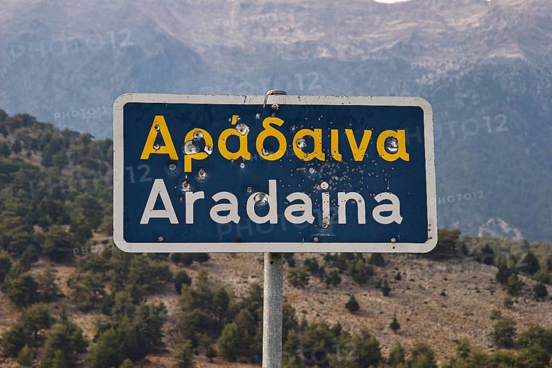 Damaged road sign with Greek and Latin lettering in front of a mountain landscape, Aradena Gorge, Aradena, Sfakia, Crete, Greece, Europe