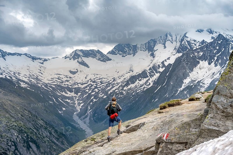 Mountaineer on hiking trail, view of glaciated rocky mountain peaks Hoher Weisszint and Hochfeiler with glacier Schlegeiskees, Berliner Hoehenweg, Zillertal Alps, Tyrol, Austria, Europe