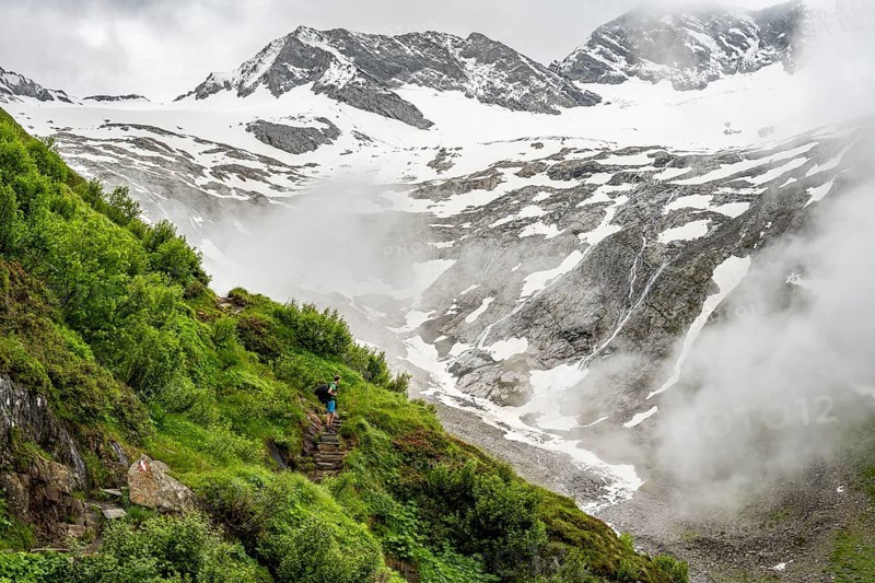 Mountaineers on a hiking trail, in the background glaciated peak Dosso Largo and glacier Schlegeiskees, cloudy atmospheric mountain landscape, ascent to Furtschaglhaus, Berliner Hoehenweg, Zillertal, Tyrol, Austria, Europe