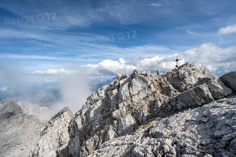 Mountaineer on the rocky summit of the Watzmann Mittelspitze with summit cross, Watzmann crossing, Berchtesgaden National Park, Berchtesgaden Alps, Bavaria, Germany, Europe