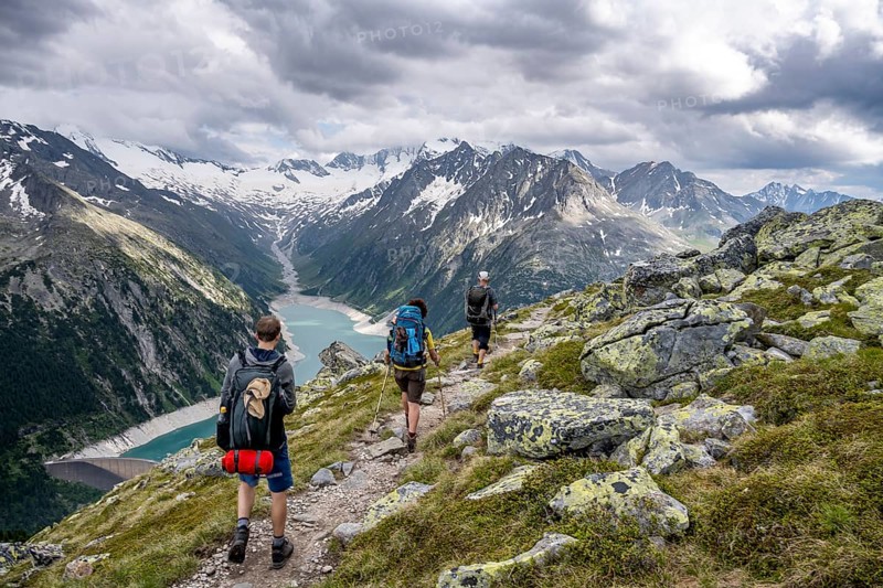 Mountaineer on hiking trail, view of Schlegeisspeicher, glaciated rocky mountain peaks Hoher Weisszint and Hochfeiler with glacier Schlegeiskees, Berliner Hoehenweg, Zillertal Alps, Tyrol, Austria, Europe