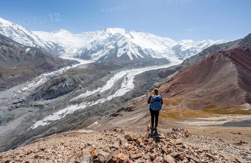 Mountaineer at Traveller's Pass with view of impressive mountain landscape, high mountain landscape with glacier moraines and glacier tongues, glaciated and snow-covered mountain peaks, Lenin Peak and Peak of the XIX Party Congress of the CPSU, Trans Alay Mountains, Pamir Mountains, Osh Province, Kyrgyzstan, Asia
