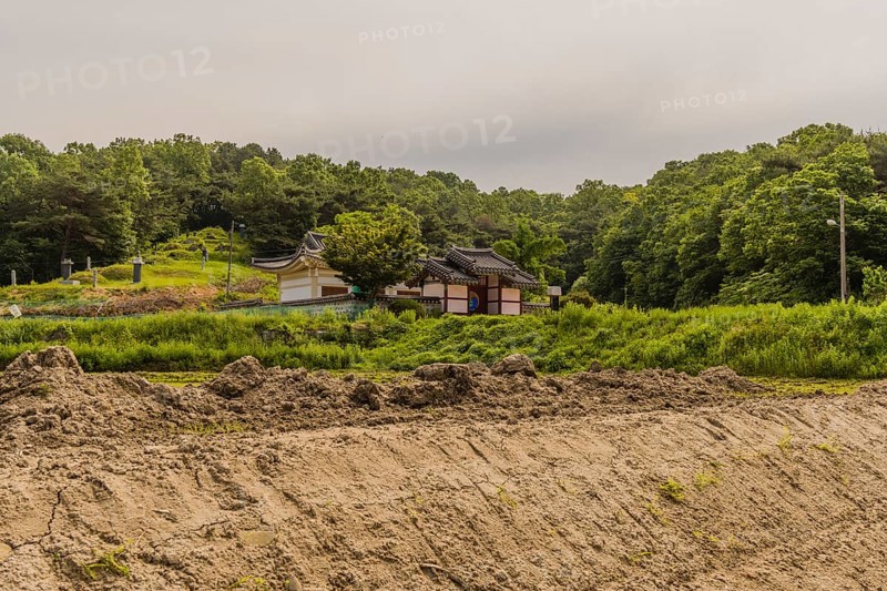 Daejeon, South Korea, May 22, 2018: Korean building with perimeter wall and ceramic tile roof in front of small family grave site in rural South Korea, Asia