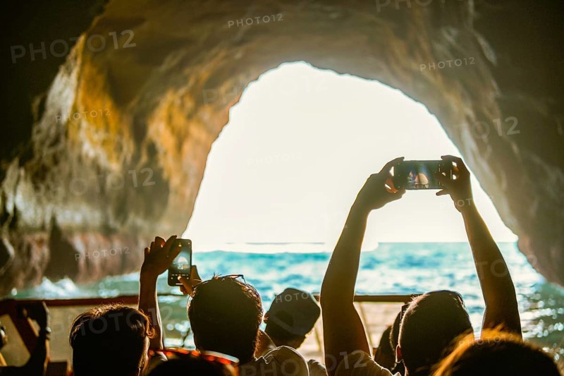 Tourist sightseeing and taking photos with smartphones inside the cave in the Algarve coast, Albufeira, Portugal, Europe