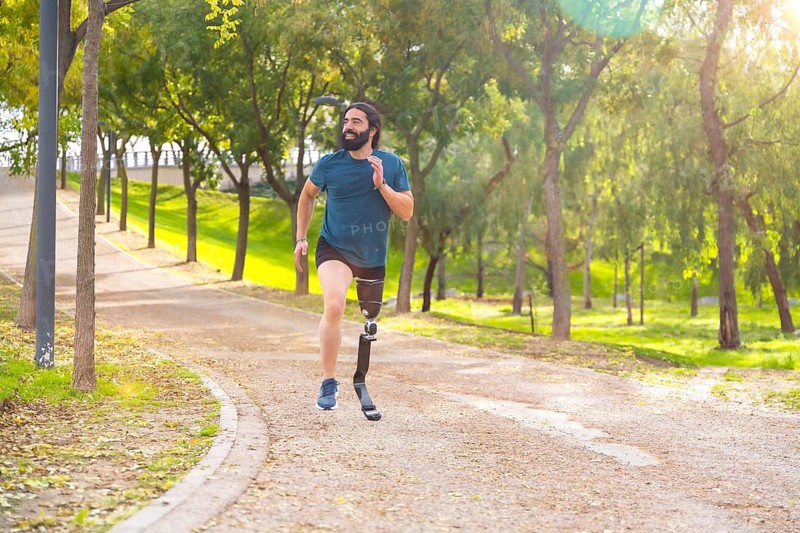 Sportsman with a artificial leg running along a path in an urban park