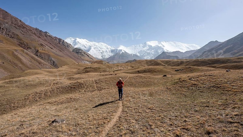 Mountaineers in the Achik Tash valley, in the background glaciated and snow-covered mountain peak Lenin Peak and Peak of the XIX Party Congress of the CPSU, Trans Alay Mountains, Pamir Mountains, Osh Province, Kyrgyzstan, Asia