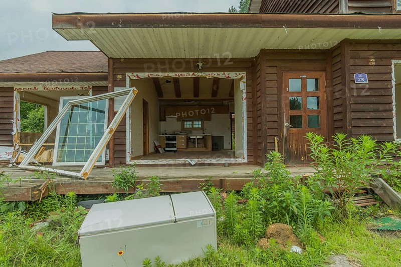 Daejeon, South Korea, June 29, 2018: Old refrigerator laying in front of abandoned two story house, Asia
