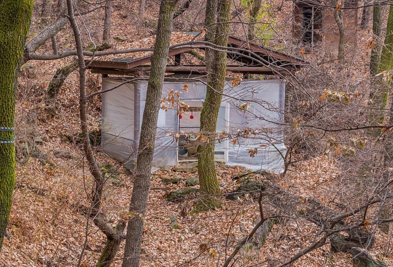 Wooden building wrapped in heavy duty plastic for use by hikers in mountainous woodland park