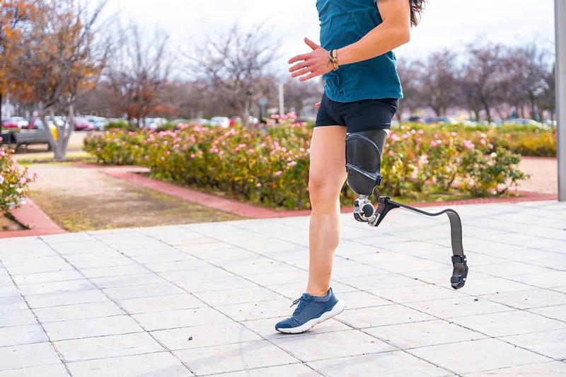 Side view of the lower part of a disabled person with prosthetic leg running in an urban park