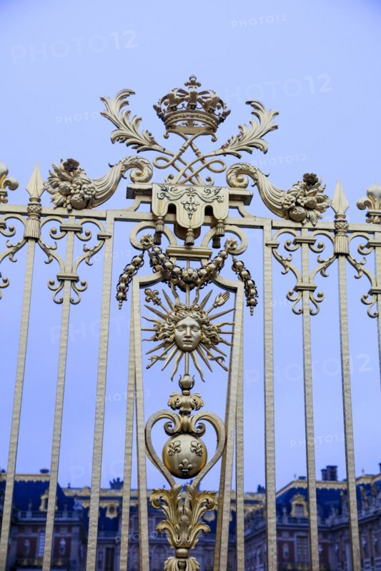 Emblem of the Sun King with Apollo's head, sunbeams and sceptre with French lily on the royal grille, Chateau de Versailles, Yvelines department, Ile-de-France region, France, Europe
