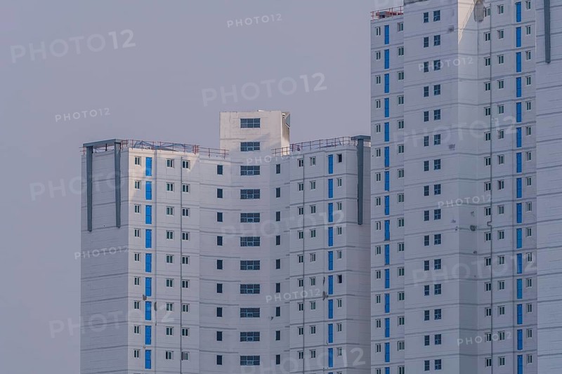 New highrise apartments with unfinished white concrete exterior walls and blue coverings on widow frames in the Shintanjin area of Daejeon, South Korea, Asia