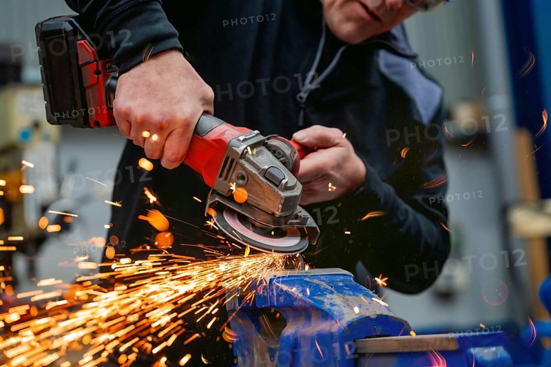 Close-up of a worker using an electric wheel grinding in a factory
