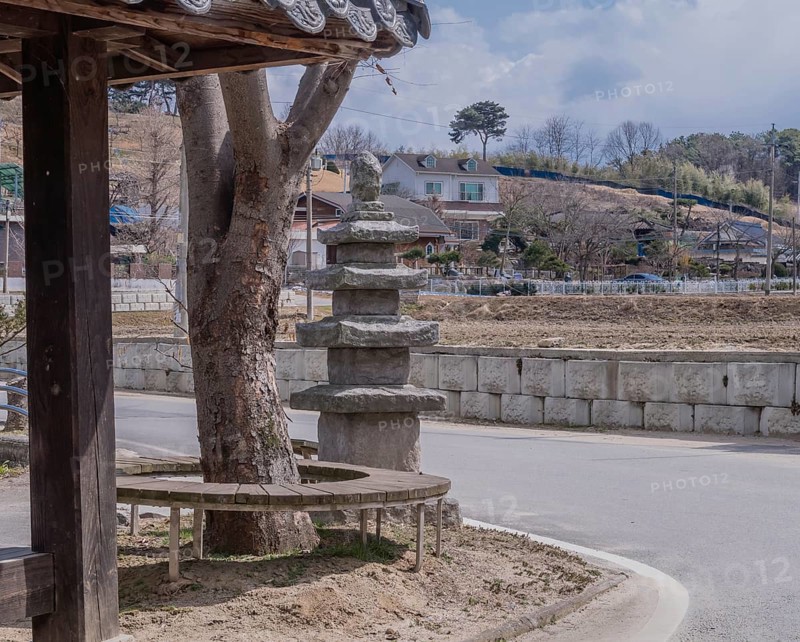 Five story concrete pagoda next to tree in public park on corner of rural street