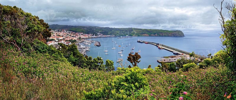 Panoramic view from Monte da Guia to a coastal town Horta with harbour and sailing boats, surrounded by green vegetation, Monte da Guia, Horta, Faial, Azores, Portugal, Europe