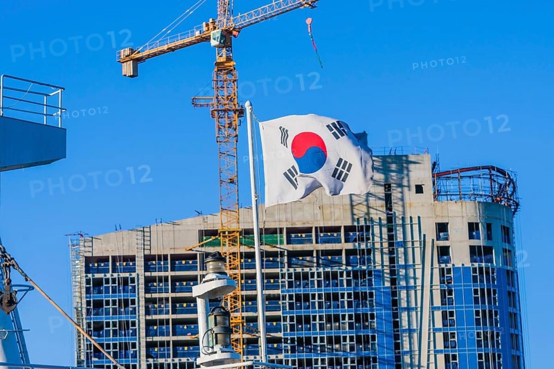 Korean flag on flying from a ship in front of a construction crane attached to a building under construction