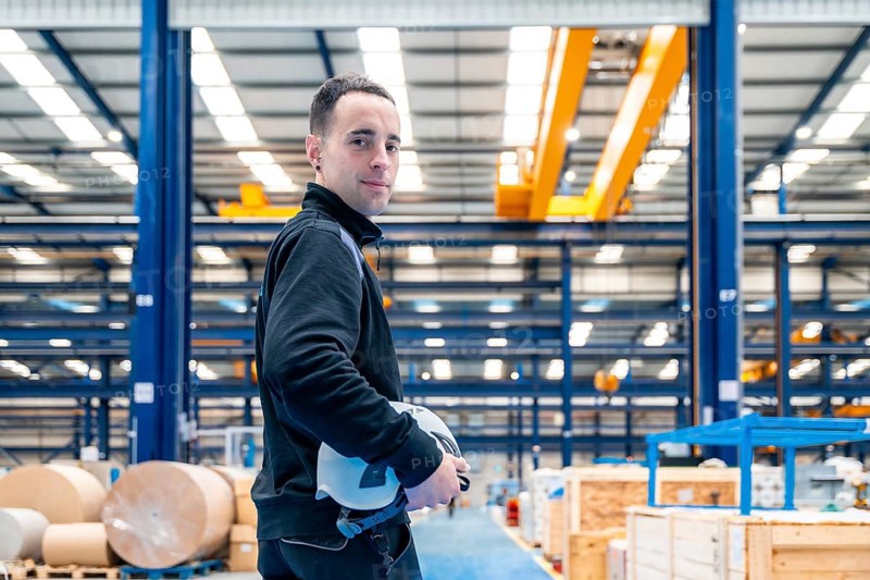 Worker turning to smile at camera standing proud in a logistic center