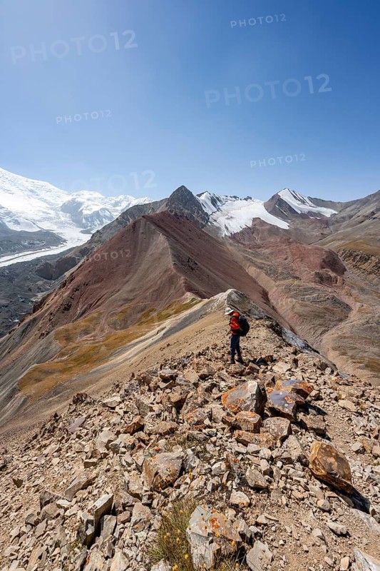 Mountaineer at Traveller's Pass with view of impressive mountain landscape, high mountain landscape with glacier moraines and glacier tongues, glaciated and snow-covered mountain peaks, Lenin Peak, Trans Alay Mountains, Pamir Mountains, Osh Province, Kyrgyzstan, Asia