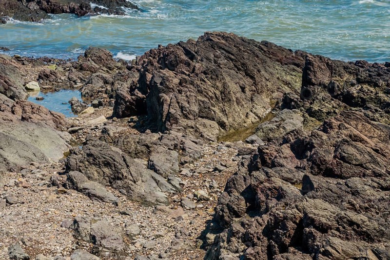 Craggy jagged shoreline with ocean in background on sunny day