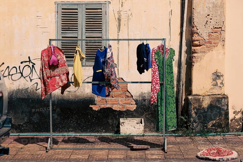 Laundry hung to dry outside in front of a weathered wall on the street side of Kampot Cambodia, showing the candid authentic khmer daily life, culture and lifestyle