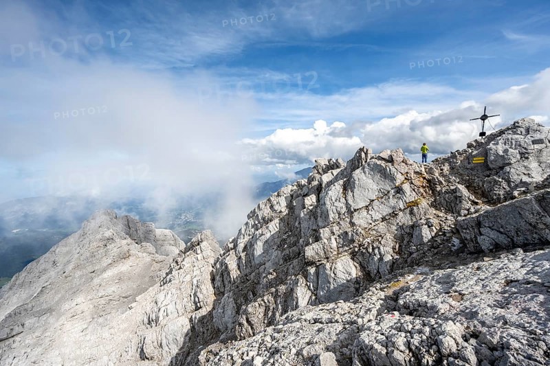 Mountaineer on the rocky summit of the Watzmann Mittelspitze with summit cross, Watzmann crossing, Berchtesgaden National Park, Berchtesgaden Alps, Bavaria, Germany, Europe