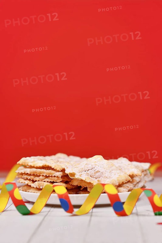Fried Italian dessert snack for carnival season called 'Galani', ' Chiacchiere' or 'Crostoli' in front of red background. Also known as Angel Wings pastry