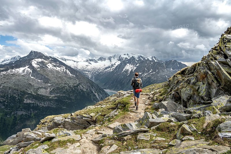 Mountaineer on hiking trail with snow, Berliner Hoehenweg, mountain landscape with glaciated peaks Hochfeiler and Hoher Weisszint, Zillertal Alps, Tyrol, Austria, Europe