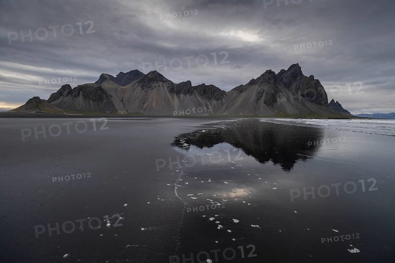 Vestrahorn, mountains with black lava sand, reflection in the water, south coast of Iceland