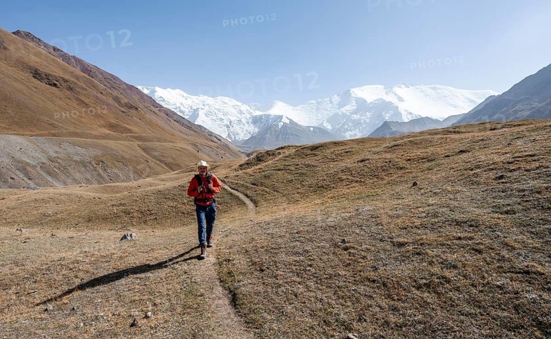 Mountaineers in the Achik Tash valley, in the background glaciated and snow-covered mountain peak Lenin Peak and Peak of the XIX Party Congress of the CPSU, Trans Alay Mountains, Pamir Mountains, Osh Province, Kyrgyzstan, Asia