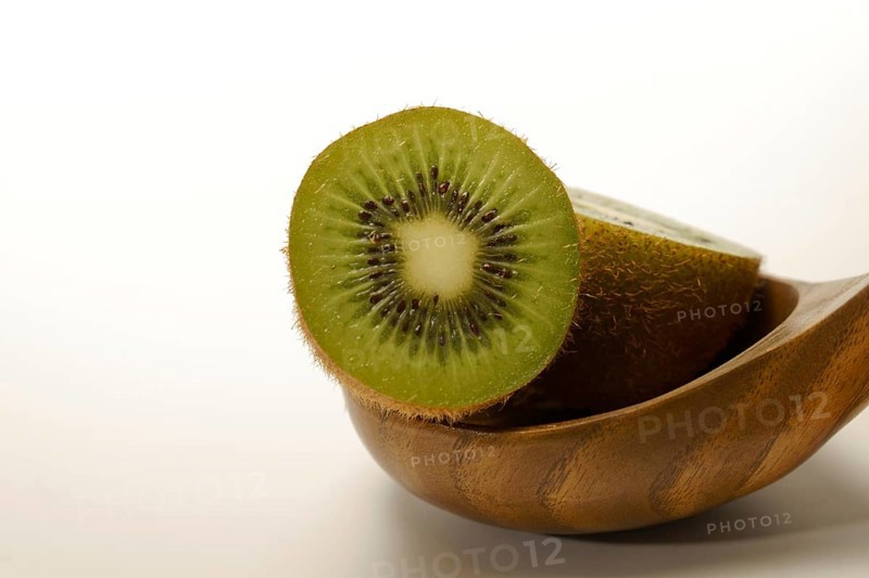 Close-up of a fresh kiwi cut in half in a wooden spoon isolated on a white background and copy space