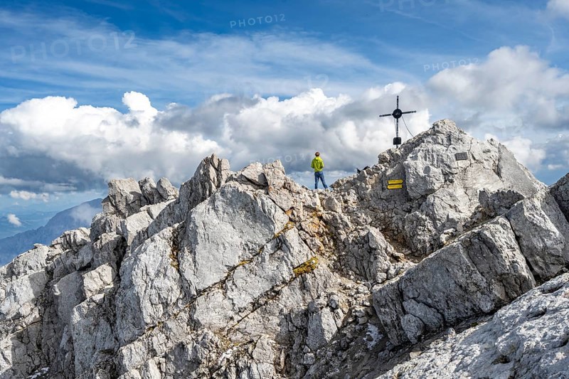 Mountaineer on the rocky summit of the Watzmann Mittelspitze with summit cross, Watzmann crossing, Berchtesgaden National Park, Berchtesgaden Alps, Bavaria, Germany, Europe
