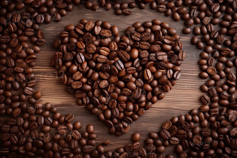 A heart-shaped arrangement of rich, dark coffee beans set against a contrasting wooden background, symbolizing love for coffee, AI generated