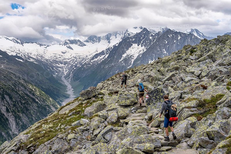 Mountaineer on hiking trail, view of glaciated rocky mountain peaks Hoher Weisszint and Hochfeiler with glacier Schlegeiskees, Berliner Hoehenweg, Zillertal Alps, Tyrol, Austria, Europe