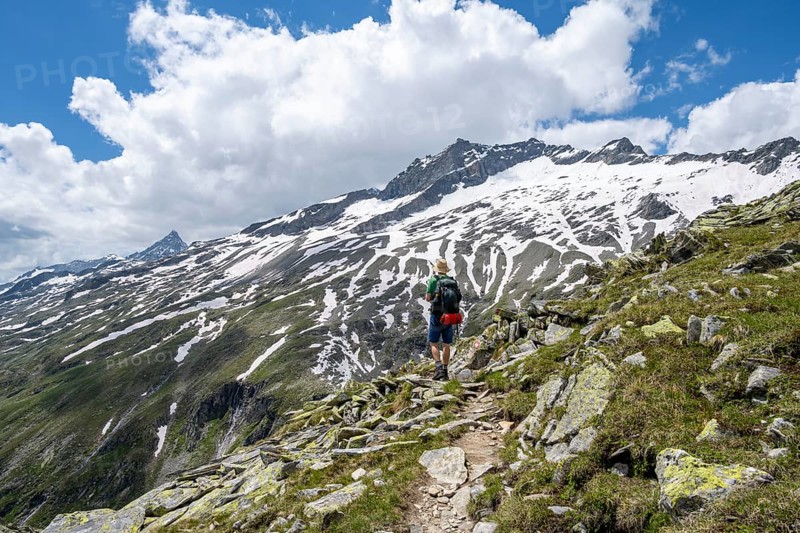 Mountaineer on rocky hiking trail, Berliner Hoehenweg, mountain landscape with snow-covered peak Gefrorene-Wand-Spitze, Zillertal Alps, Tyrol, Austria, Europe