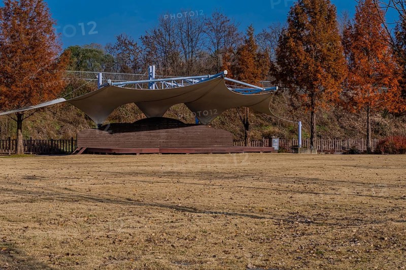 Outdoor event and performance stage with white canvas awning located in public park