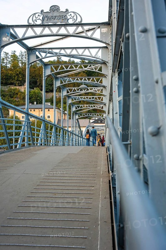 People walking across an ornate steel bridge in an urban area, Mozartsteg, Salzburg, Austria, Europe