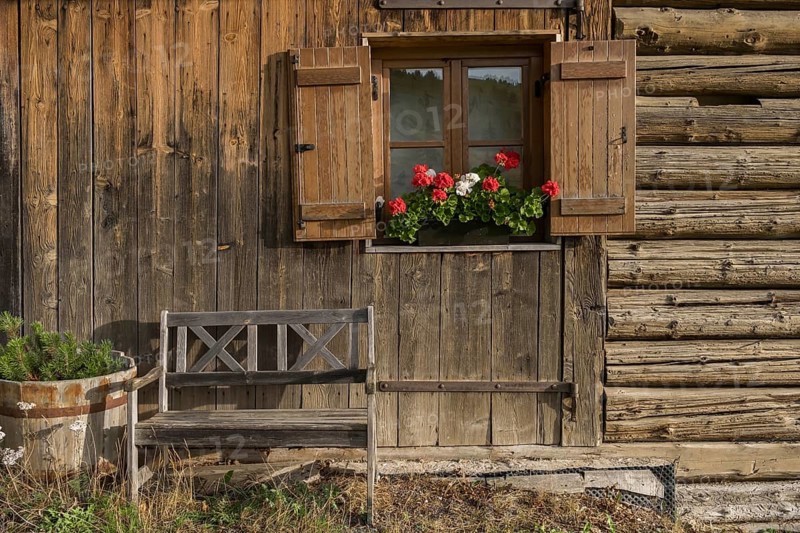 Alpine hut with wooden bench and window with shutters and geraniums, Alpe di Siusi, South Tyrol, Italy, Europe