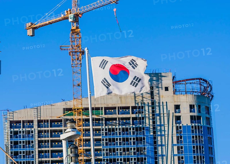 Korean flag on flying from a ship with a construction crane attached to a building under construction