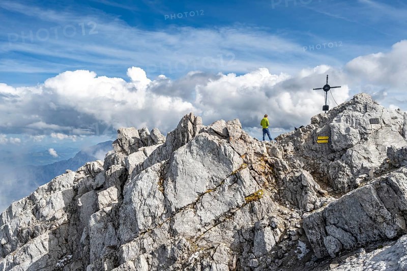 Mountaineer on the rocky summit of the Watzmann Mittelspitze with summit cross, Watzmann crossing, Berchtesgaden National Park, Berchtesgaden Alps, Bavaria, Germany, Europe