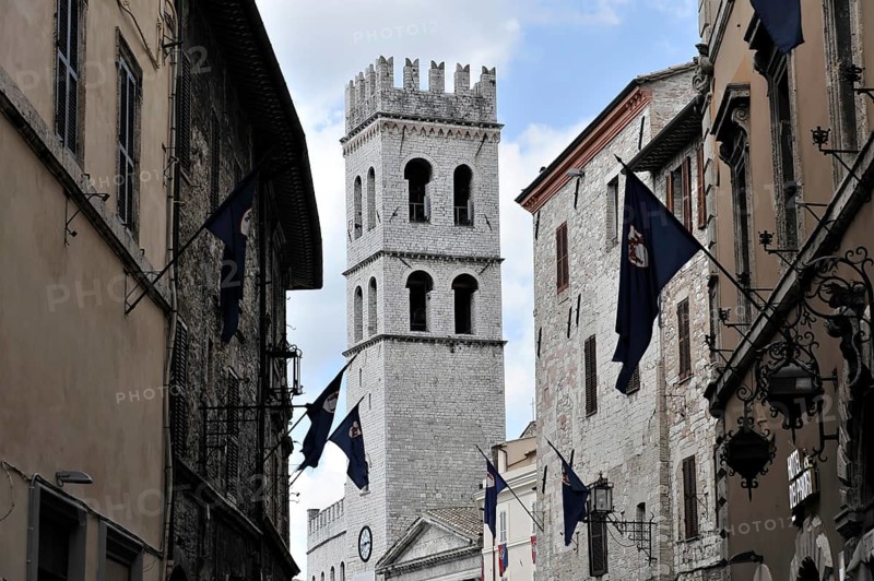 Old town alley decorated with flags, church tower of Santa Maria sopra Minerva church, city centre, old town, Assisi, Italy, Europe