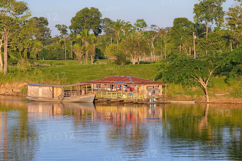 Wooden house and boat in the flooded forest along the Madeira River at sunset, Amazonas state, Brazil, South America